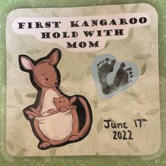 a hand and foot imprint on a sign for a baby's first kangaroo held with mom