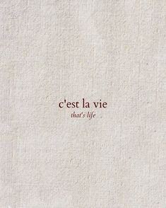 the words cest la vie are written in red ink on a white linen background