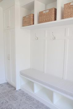 a white bench sitting in the middle of a room next to two baskets on top of it