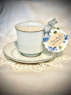 a white cup and saucer with a label on it sitting on a lace doily