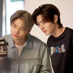 two young men standing next to each other in front of a mirror with an old camera