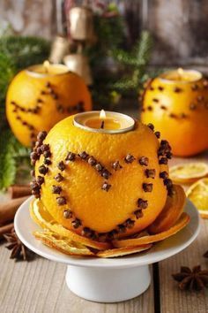 an orange is sitting on a plate with some cinnamons around it and a candle in the middle