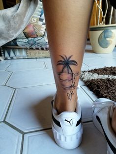 a woman's foot with a small palm tree tattoo on her left leg and the bottom part of her shoe