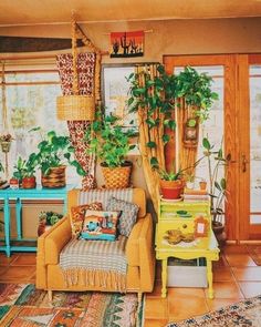 a living room filled with lots of plants next to a table and couch in front of a window