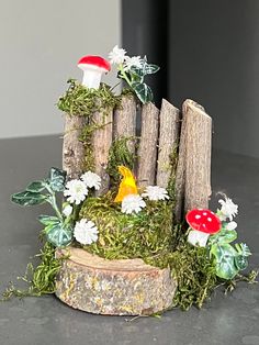 a small wooden fence with mushrooms and flowers on the mossy ground next to it