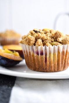 a muffin is sitting on a plate next to some fruit