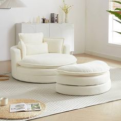 a living room filled with white furniture and pillows on top of a rug next to a window