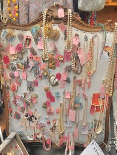 a bunch of necklaces are on display in a market stall with other items hanging from the wall