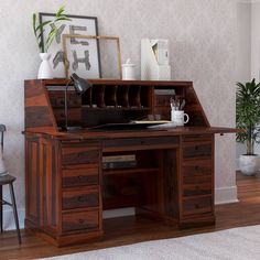 an old fashioned wooden desk with drawers in a living room next to a potted plant