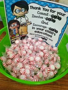 a green bucket filled with candy canes on top of a wooden table next to a sign