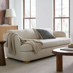 a living room filled with furniture and two large windows covered in blankets on top of them