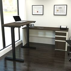 a desk with a laptop computer on it in an office space next to a window