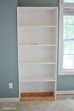 a white book shelf sitting in the corner of a room