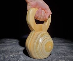 a hand holding a wooden object on top of a gray surface with a black background