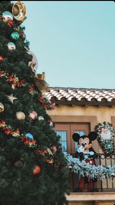 a christmas tree with mickey mouse and other decorations on it in front of a house