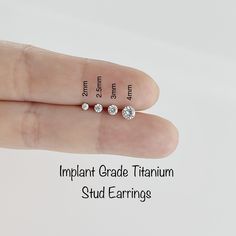 a person's hand with three diamond studs on it and the words implantnt grade titanium stud earrings