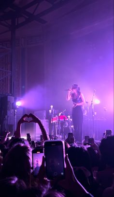 a woman standing on top of a stage holding a microphone in front of a crowd