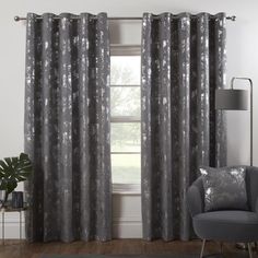 a living room with grey curtains and a chair