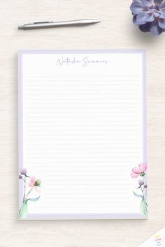 a notepad with watercolor flowers on it next to a pen