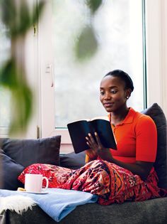 a woman sitting on a couch reading a book