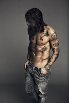 a shirtless man with tattoos on his chest and arms is posing for the camera