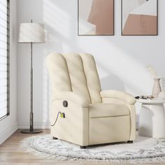 a living room with a white chair and two pictures on the wall above it,