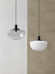 two pendant lights hanging from the ceiling in front of a white wall and beige wall