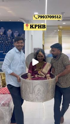 two men and a woman standing in front of a large metal bowl