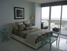 a bedroom with a bed, chair and window overlooking the cityscape in front of it