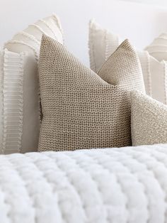 a close up of pillows on a bed in a room with white walls and furniture