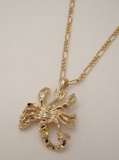 a gold plated necklace with a lobster on it's side and a chain around the neck