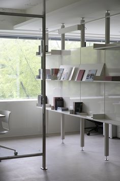 an office with glass walls and shelves filled with books