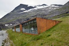 an unusual building on the side of a mountain with glass windows in front of it