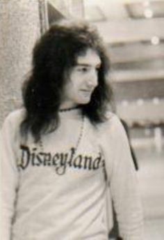 an old black and white photo of a woman with long hair wearing a disneyland shirt