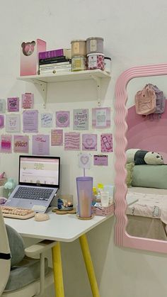 a laptop computer sitting on top of a white desk in front of a pink mirror