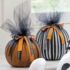 two pumpkins decorated with black and white stripes, one has a bow on it