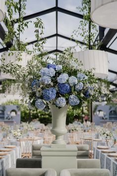 a vase filled with blue flowers sitting on top of a table covered in white linens