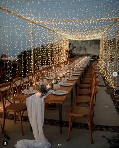 a long table is set with candles, plates and place settings for an outdoor dinner