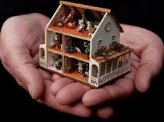 a person holding a small doll house in their hands