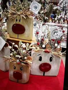 three christmas gift bags with reindeer faces on them are sitting on a red tablecloth