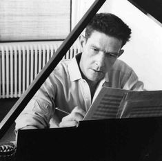 a black and white photo of a man sitting at a piano