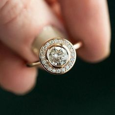 a close up of a person's hand holding a ring with a diamond in it