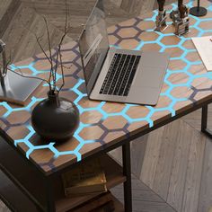 a laptop computer sitting on top of a wooden table next to a vase with flowers