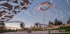 people are riding bicycles under an artistic structure