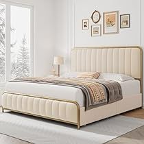 a bedroom with white walls and wood floors, a bed in the foreground has a beige upholstered headboard