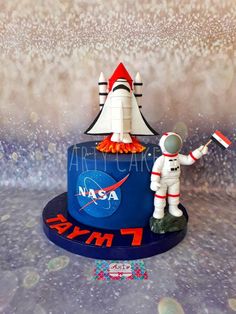 a nasa cake with an astronaut and rocket ship on it's top, as well as a flag