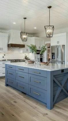 a large kitchen with white cabinets and blue island