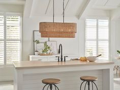 a kitchen island with two stools under a light fixture