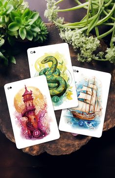 three tarot cards with an image of a snake on one and a ship on the other