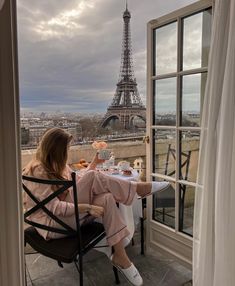 a woman sitting at a table with food in front of the eiffel tower